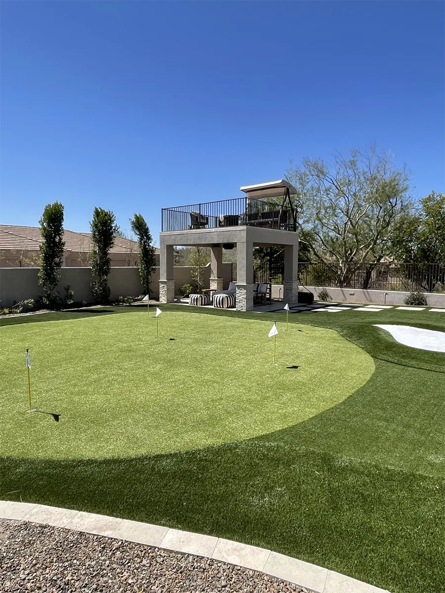 Synthetic turf putting green with patio raised overlooking it.